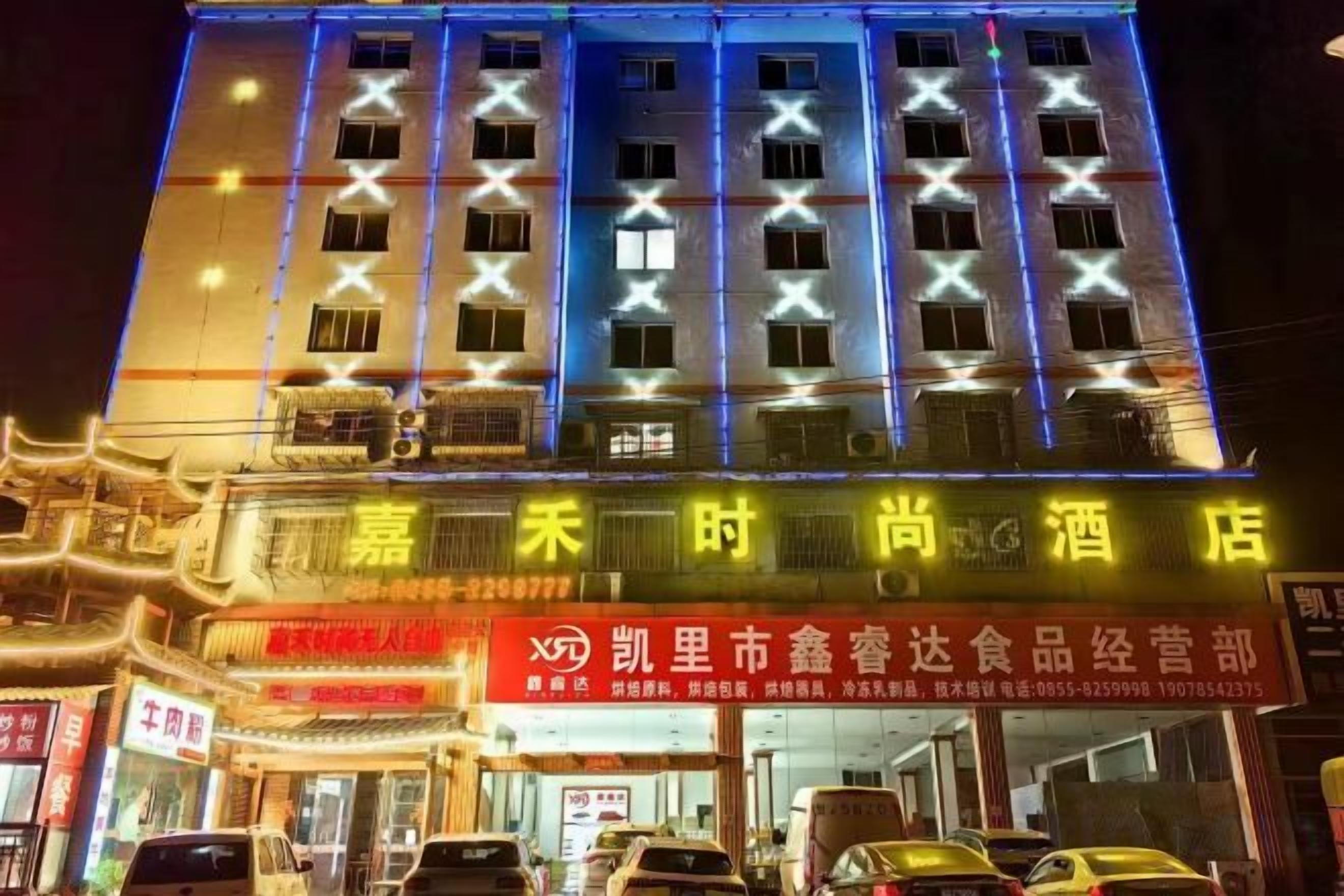 A hotel with multiple floors, illuminated windows, and a prominent sign with Chinese characters.