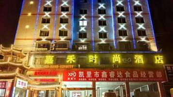 A hotel with multiple floors, illuminated windows, and a prominent sign with Chinese characters.