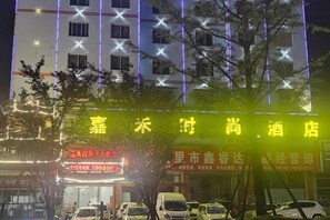 Un hotel con una fachada luminosa, varias ventanas y un letrero con caracteres chinos.