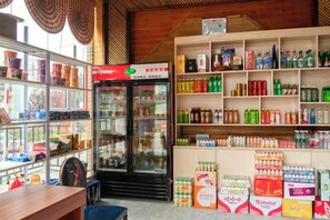 A refrigerated display case, shelves stocked with beverages, and a counter with various items.