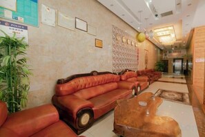 A lobby with leather sofas, a wooden coffee table, and framed certificates on the wall.
