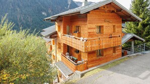 Un chalet en bois doté d’un balcon, situé dans un cadre montagneux.