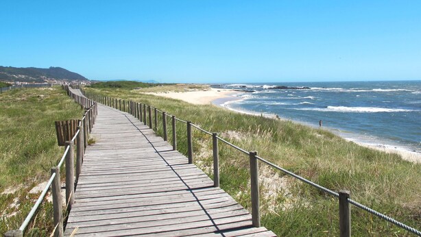 Una pasarela de madera que conduce a una playa con olas rompiendo en la orilla.