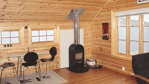 A log cabin interior with a wood stove, a dining area with chairs, and large windows. - Hardangerrorbu by Interhome (Tjoflot)