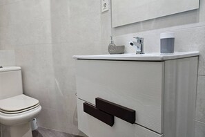 Une salle de bain comprenant des toilettes, un lavabo avec un robinet et un miroir au-dessus du lavabo.