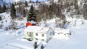 A snow-covered landscape with a white house and a red barn.