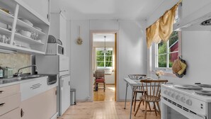 A modern kitchen with white cabinets, a wooden floor, and a dining area with a table and chairs.
