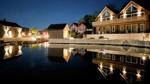 A waterfront property with wooden houses, a calm reflective pool, and a wooden dock. - Vacation home Pale by Interhome (Langevåg)