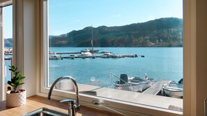 Una cocina con un ventanal que da a un puerto deportivo con barcos.