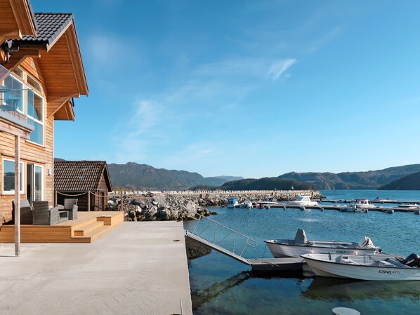 A wooden building with a balcony, a dock with boats, and a clear view of mountains in the background. - Gurevika by Interhome (Huglo)