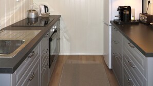 Cozinha compacta com fogão, chaleira e cafeteira.