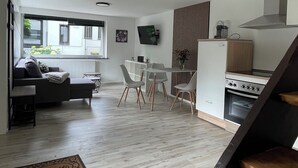 A modern kitchen with a dining area, wooden flooring, and a large window. - Oase im Grünenhinterhof, EG, Ruhe, Terrasse, Carport, Free Paytv, Kaffee&tee, (Duisburg)