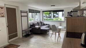 A compact living space with a sofa, a dining table, and a kitchenette. - Oase im Grünenhinterhof, EG, Ruhe, Terrasse, Carport, Free Paytv, Kaffee&tee, (Duisburg)
