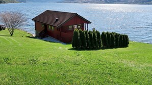 A red cabin by a lake with a clear view of mountains in the background. - Vacation home Nanna by Interhome (Risnes)