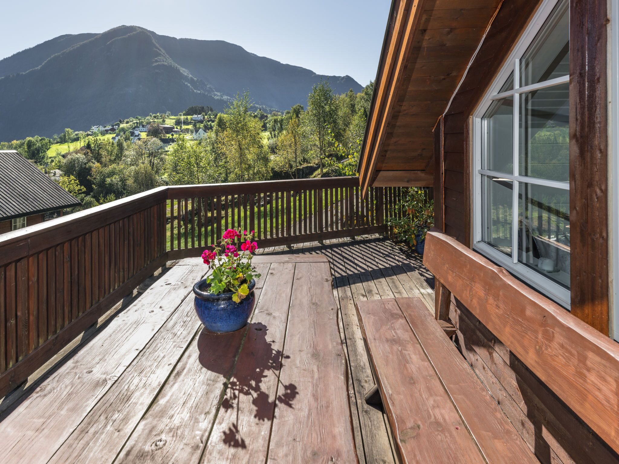 A wooden deck with a potted plant and a view of a mountainous landscape.