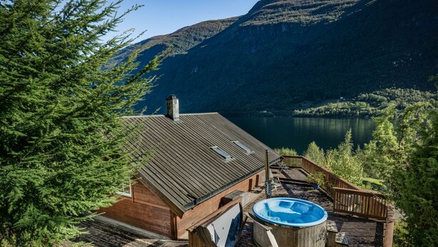 Een chalet met een hottub en een terras met uitzicht op een meer.