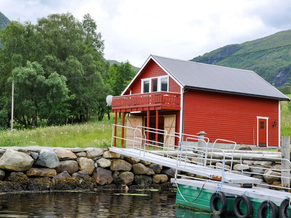 A red wooden building with a balcony, a dock, and a stone wall.