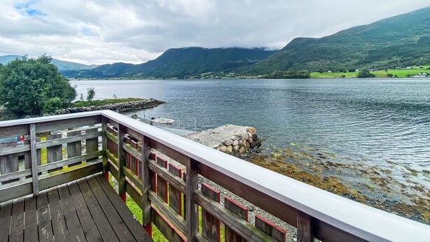 A wooden deck overlooking a lake with mountains in the background. - Naustet by Interhome (Åheim)