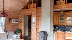 Interior acogedor de una cabaña con sala de estar, cocina y habitación en altillo.