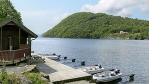 Una cabana vora un llac amb un moll i barques.