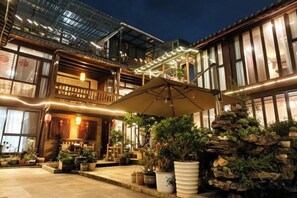 A traditional building with a balcony, outdoor seating, and potted plants.