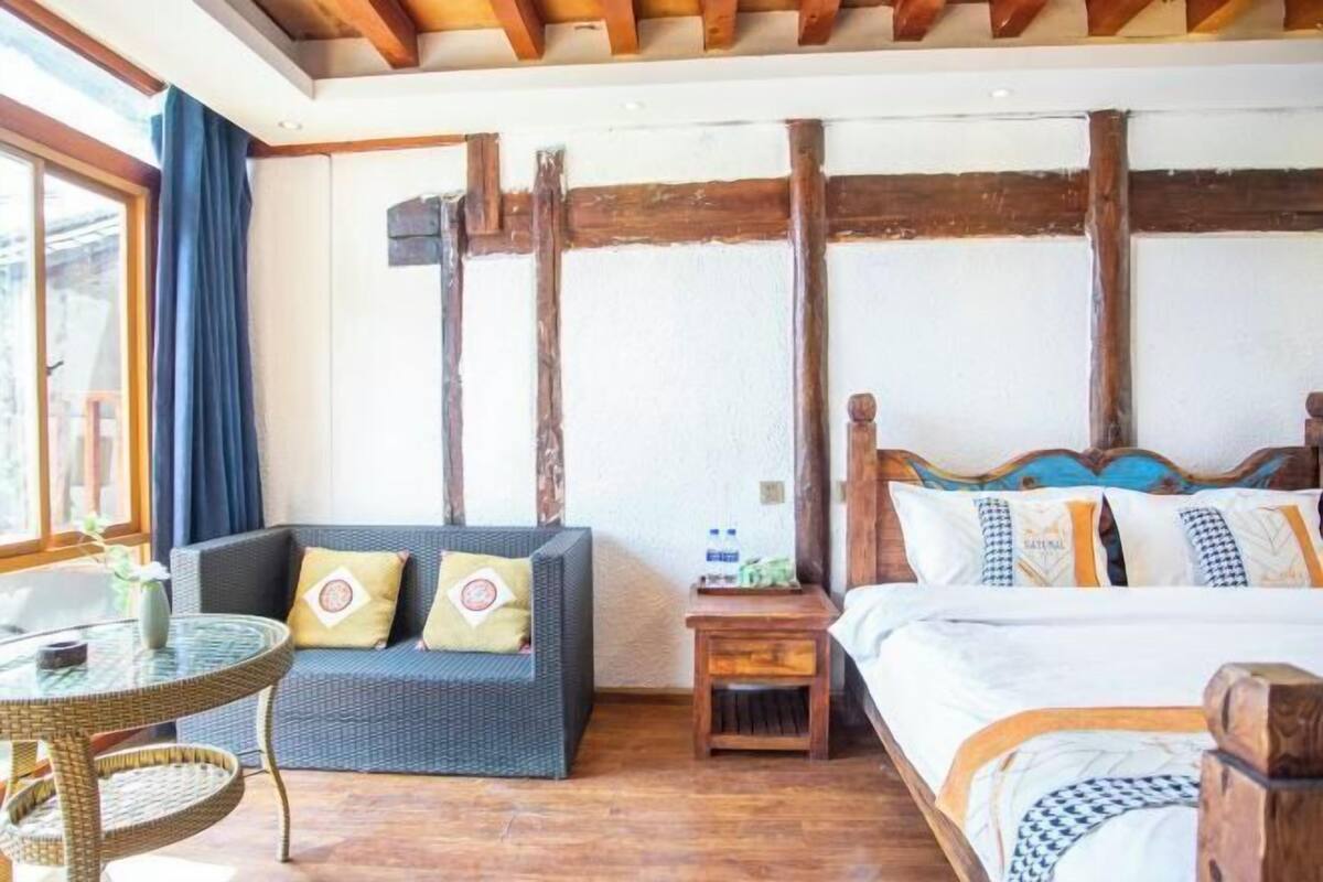 A hotel room with a bed, a sofa, a small table, and a window.