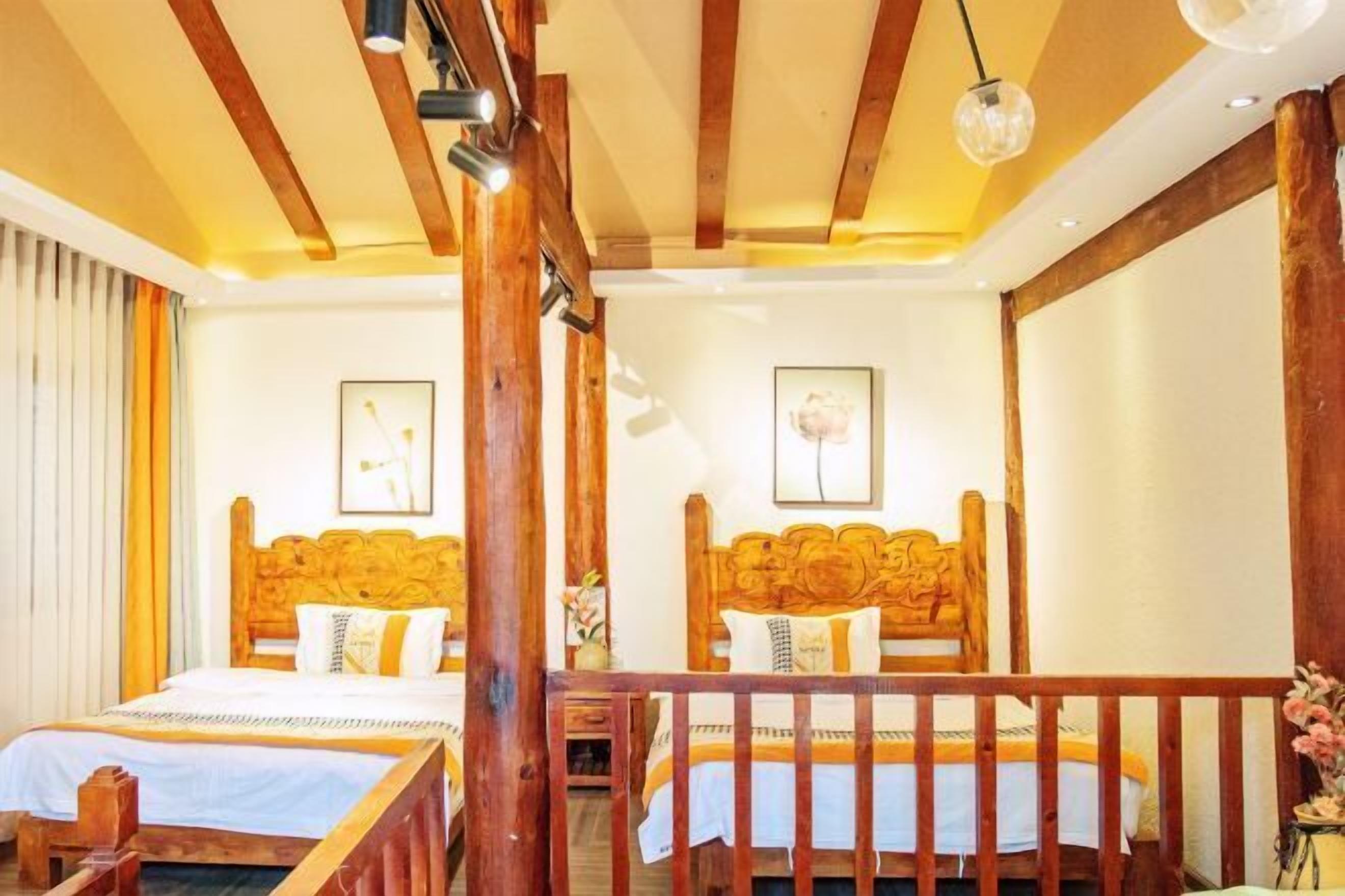 A hotel room with two wooden beds, a wooden railing, and a ceiling with exposed beams.