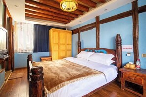 A bedroom with a wooden bed, a wooden wardrobe, a bedside table with a bottle, and a lamp on the ceiling.