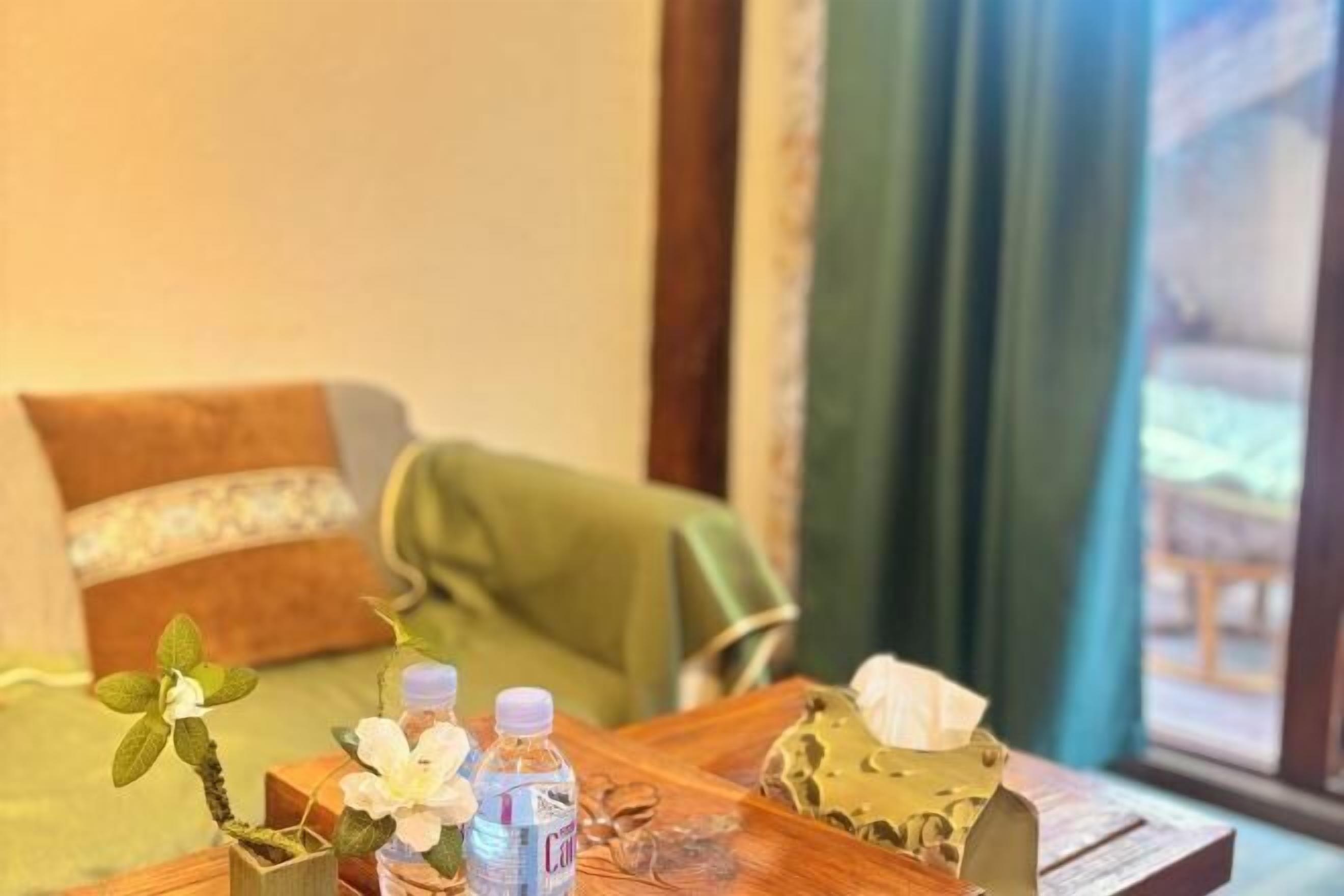 A wooden table with a potted orchid, two water bottles, and a tissue box.