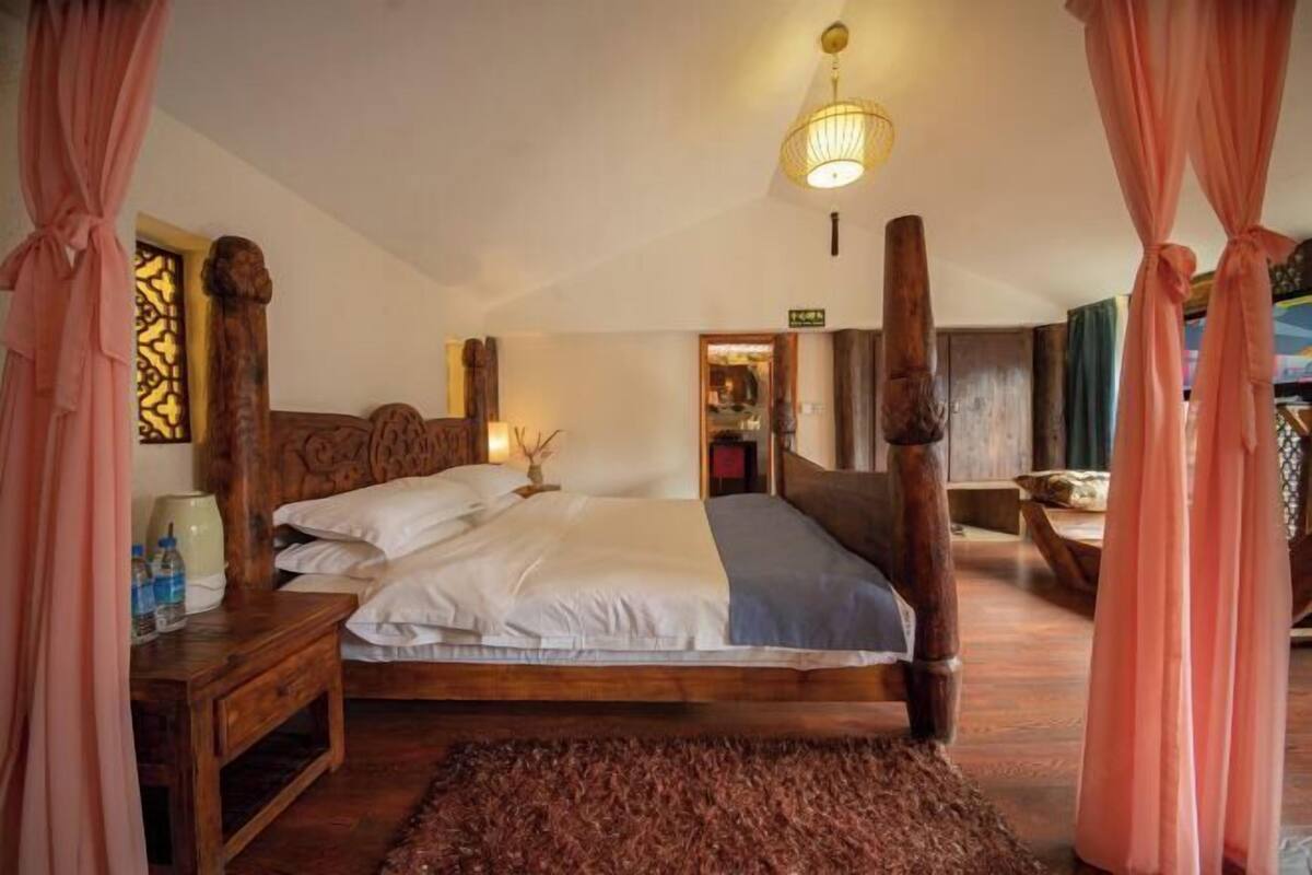 A bedroom with a wooden bed, a nightstand, a lamp, and a decorative headboard.