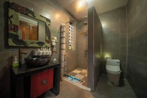 A bathroom with a shower, toilet, and a sink with a mirror.