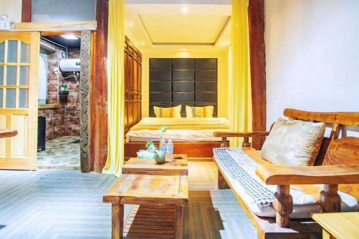 A cozy room with a bed, wooden furniture, and a stone wall.