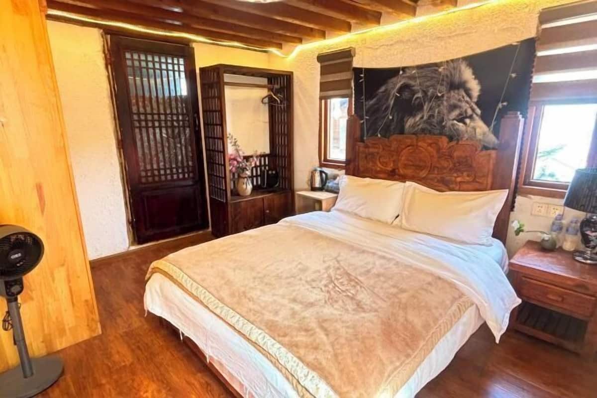 A bedroom with a large bed, wooden headboard, and a fan.