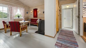 Une pièce chaleureuse avec des murs et un plafond en bois, un canapé, une table avec des chaises et un tapis.