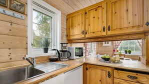 Une cuisine avec des meubles en bois, un évier en acier inoxydable, une machine à café et un four à micro-ondes.