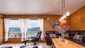 Une pièce chaleureuse avec un canapé en cuir, une table à manger et une vue sur les montagnes grâce à de grandes fenêtres.