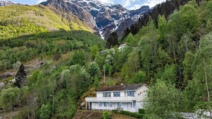 Une maison à l’extérieur blanc, située sur une colline, d’où l’on peut admirer une montagne et une vallée.