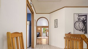 Un couloir avec des chaises en bois, un banc en bois, une horloge et un tableau encadré accroché au mur.