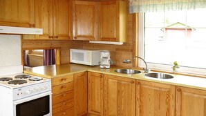 A kitchen with wooden cabinets, a stove, a microwave, and a sink.