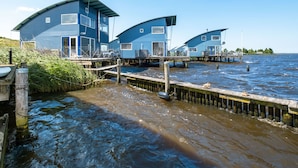 A waterfront property with multiple blue buildings, wooden walkways, and a dock extending into the water.