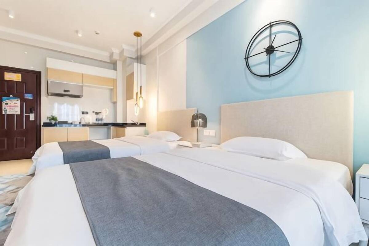 Ein Hotelzimmer mit zwei Betten, einer Küchenzeile, einer Wanduhr und einer Tür mit einem Schild.