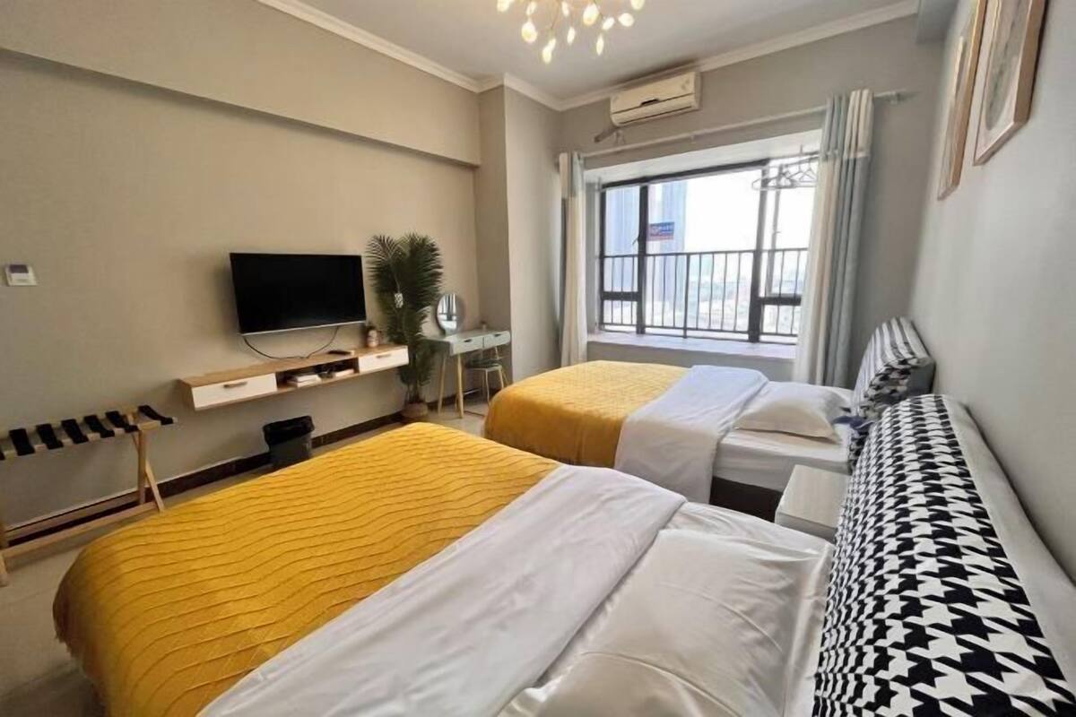 Ein Hotelzimmer mit zwei Betten, einem Fernseher, einem Fenster mit Blick und einem Balkon.
