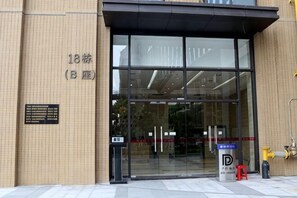 A building entrance with a glass door, a fire hydrant, and a parking sign.