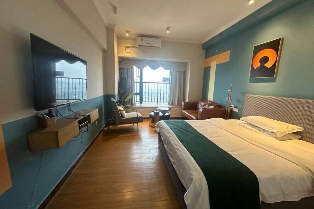 Ein Hotelzimmer mit einem großen Bett, einem flachbildfernseher an der Wand, einer Sitzecke mit Sofa und Sesseln sowie einem Balkon mit Aussicht.