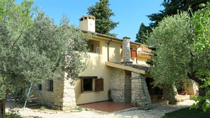 A stone building with a yellow facade, a chimney, and a small balcony.