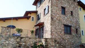 Ein Steinhaus mit Balkon, einer Treppe und einem kleinen Garten mit Blumen.