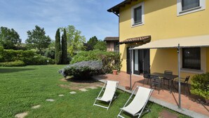 A yellow building with a patio area, two lounge chairs, and a table. - La Corte Bricca (Bilo D) by Interhome (Oltrepò Pavese)