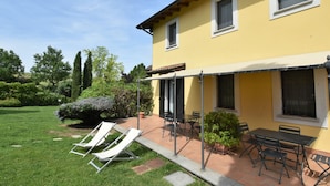 A yellow building with a patio area featuring outdoor furniture and a lawn. - La Corte Bricca (Bilo C) by Interhome (Oltrepò Pavese)