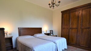 A bedroom with two beds, a wooden wardrobe, and a chandelier. - La Corte Bricca (Trilo B) by Interhome (Oltrepò Pavese)