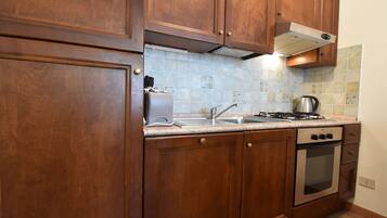 Een koelkast, een oven, een vaatwasser, kookgerei, borden en bestek